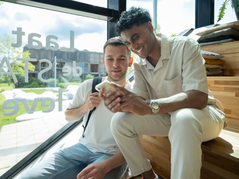 Studenten zitten samen op een mobiel en lachen om iets