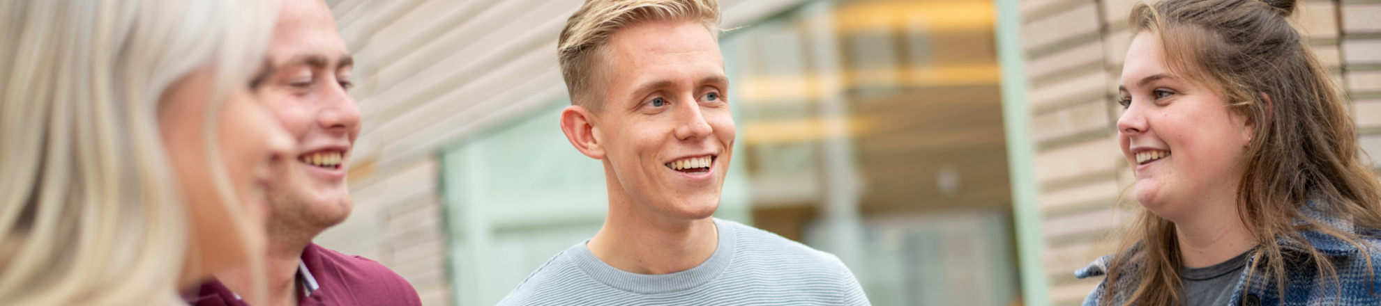 Studenten staan binnen bij Aeres Hogeschool Dronten en lachen naar elkaar. Twee jongens en twee meiden