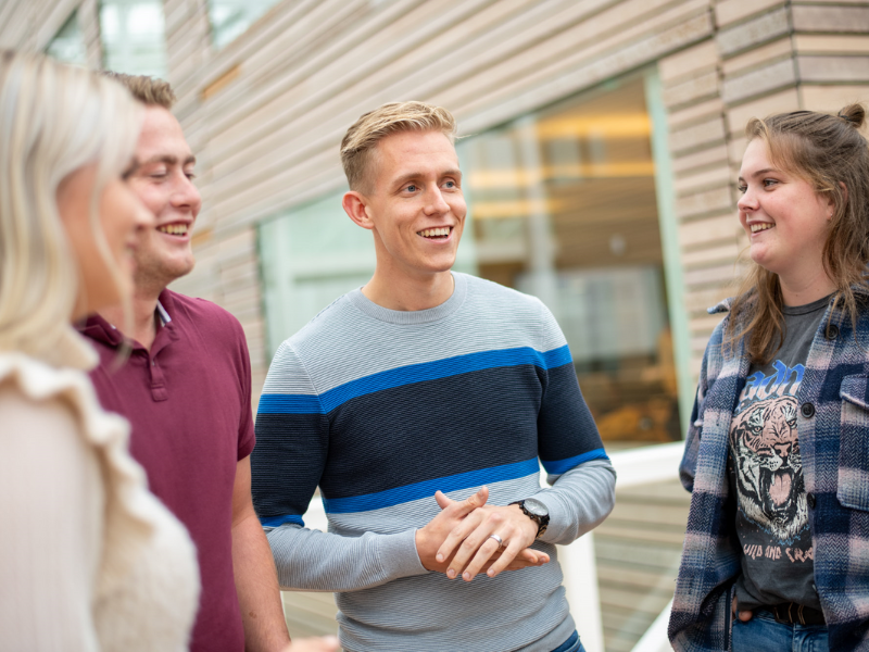 Studenten staan binnen bij Aeres Hogeschool Dronten en lachen naar elkaar. Twee jongens en twee meiden