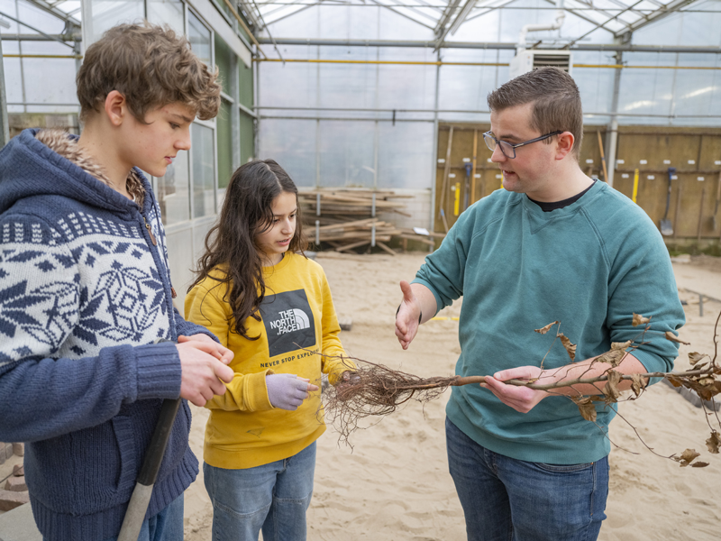Docent en kennismanager Groen legt uit aan studenten met takken in hand