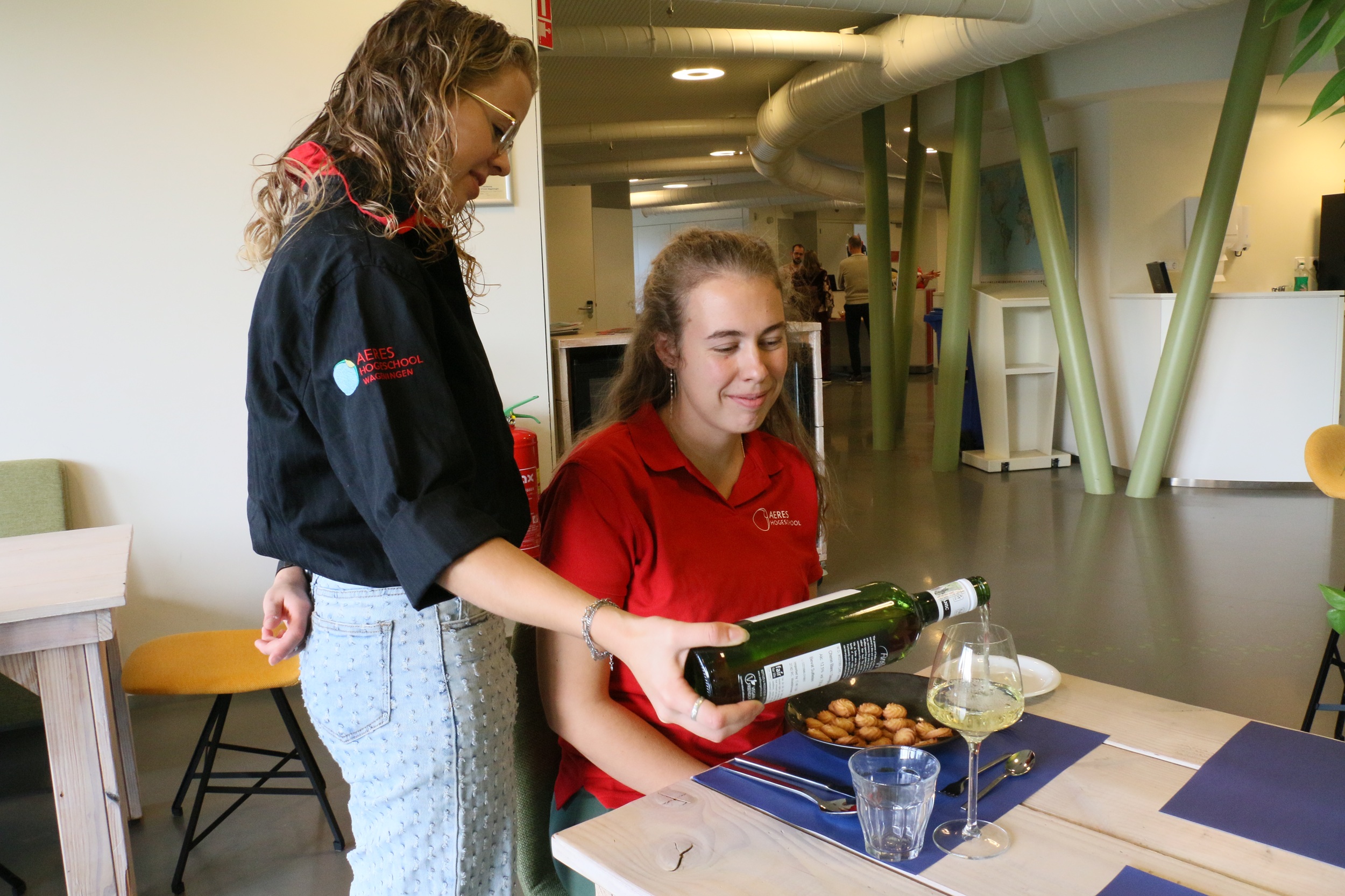 Student horeca bakkerij en recreatie schenkt wijn in aan mede student