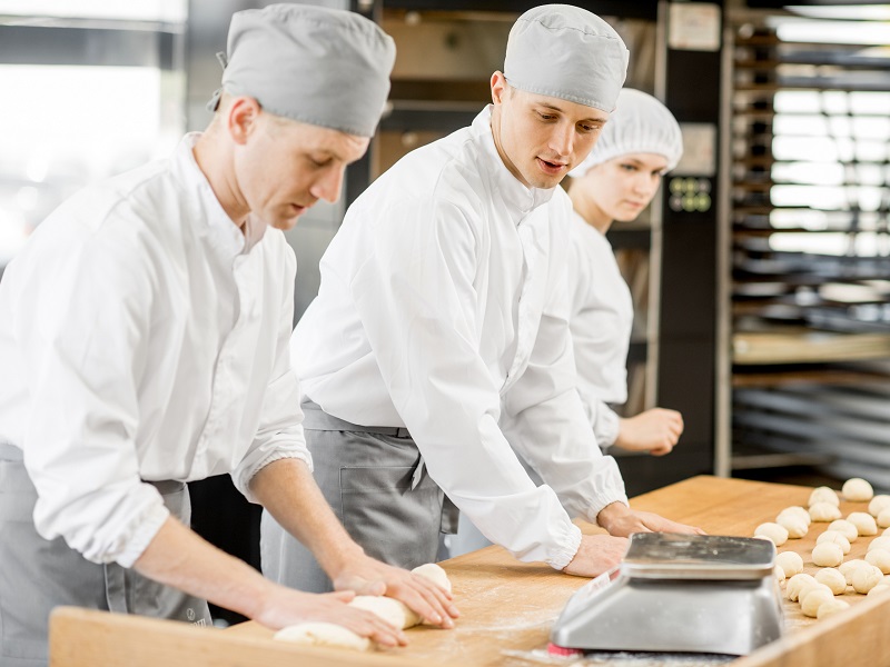 Consumptieve techniek drie bakkers in bakkerij kneden van deeg