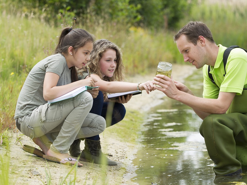 Groene sector docent met jonge leerlingen buiten bij water
