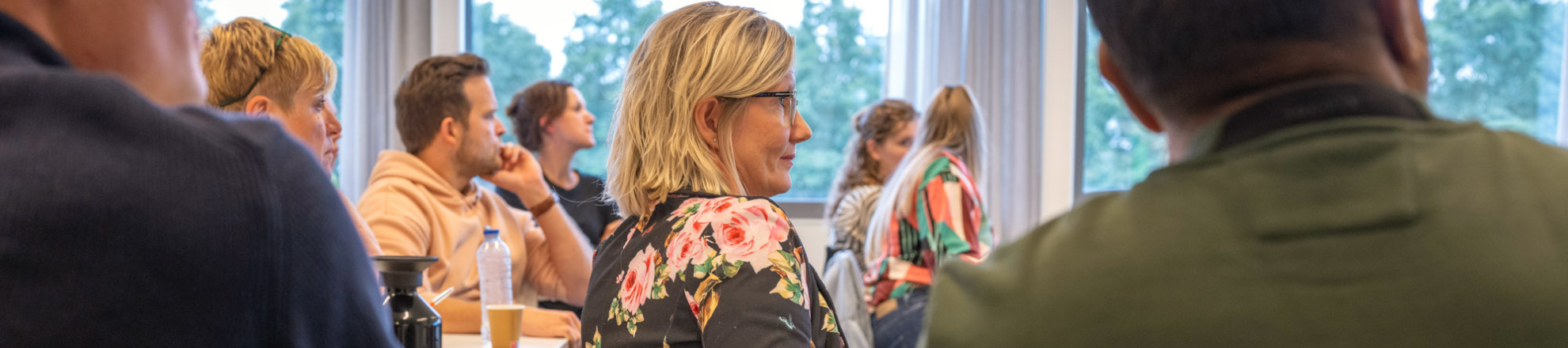 Studenten, mannen en vrouwen, zitten in de klas en kijken naar de docent