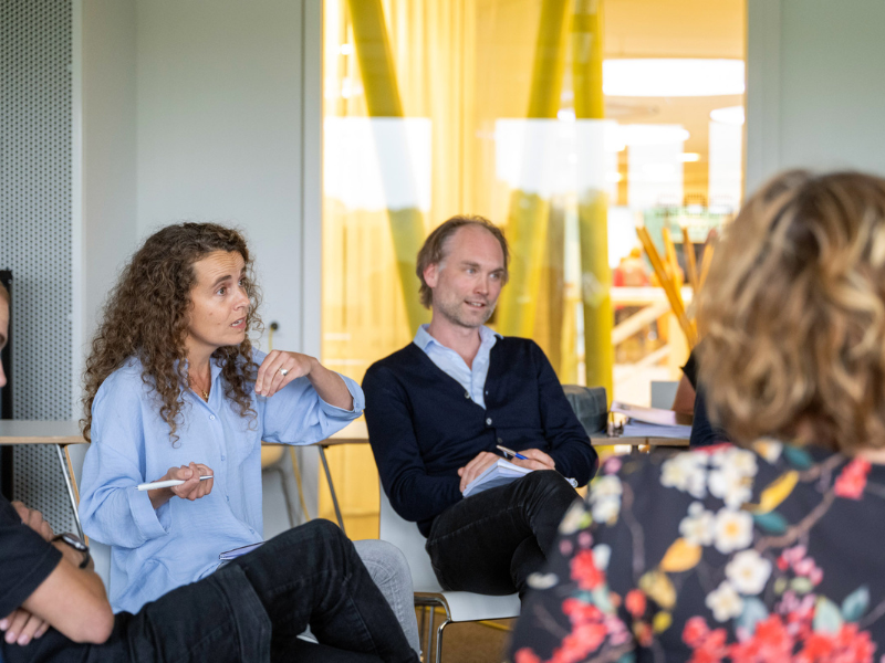 Mannelijke en vrouwelijke student zijn in gesprek met andere studenten in de klas